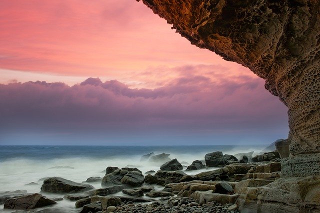 A sea with some rocks on the beach